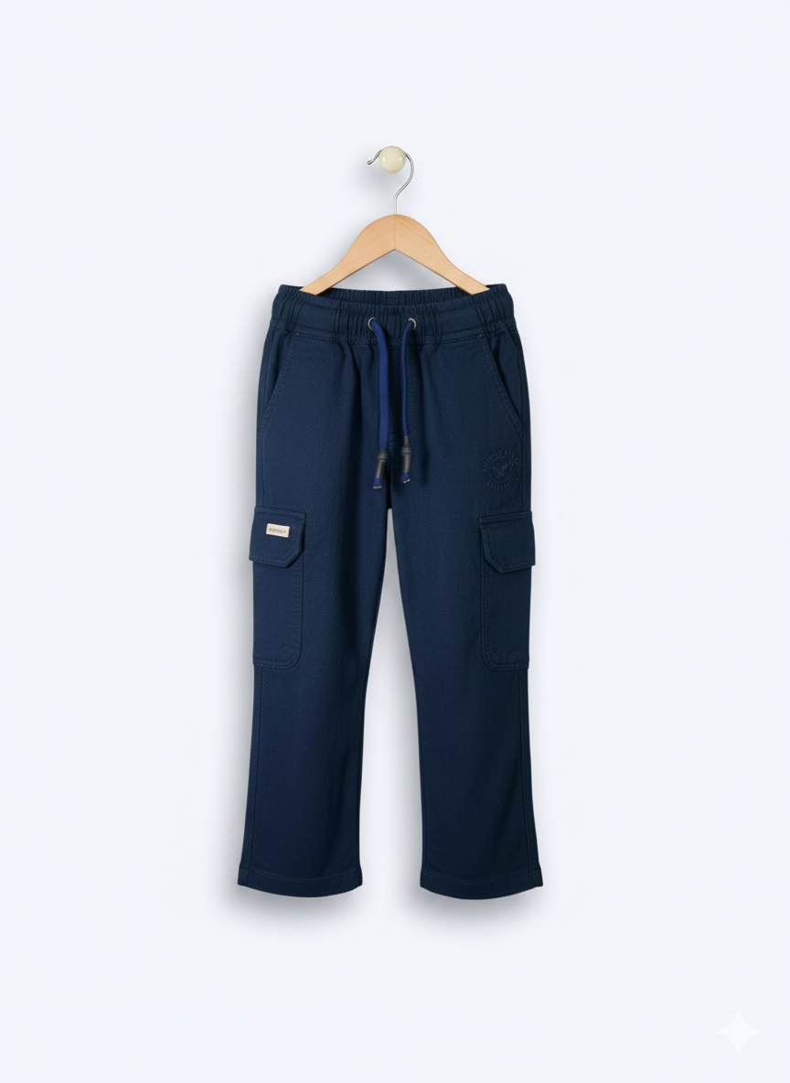 Boys' plain navy blue cargo pants made of soft fleece or knit material, hanging on a wooden hanger, showing the elastic waist and large side pockets.