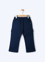 Boys' plain navy blue cargo pants made of soft fleece or knit material, hanging on a wooden hanger, showing the elastic waist and large side pockets.
