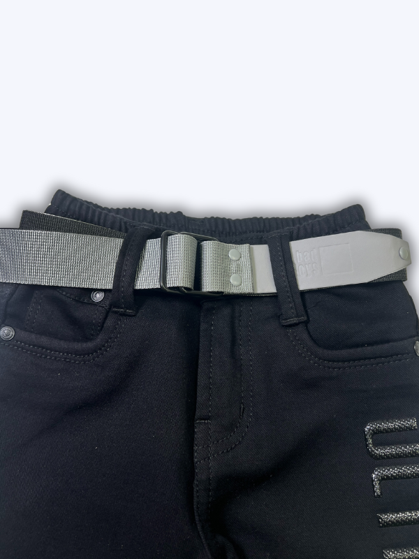 Boys' black straight-fit pants with the word 'ULTIMATE' printed/embroidered on the side, shown with an included silver-buckle belt against a white background.