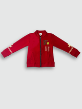 Bright red boys' zip-up jacket with black piping and gold horse emblems on the sleeves, styled over a black graphic T-shirt