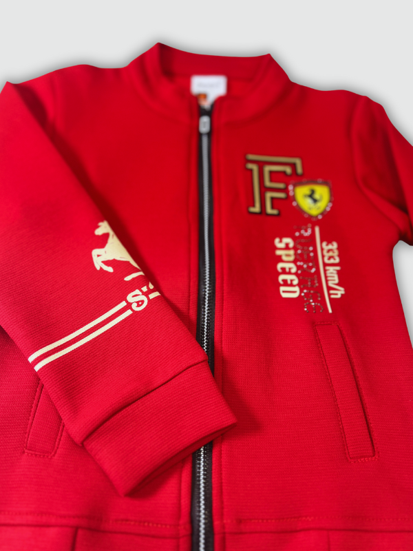 Bright red boys' zip-up jacket with black piping and gold horse emblems on the sleeves, styled over a black graphic T-shirt