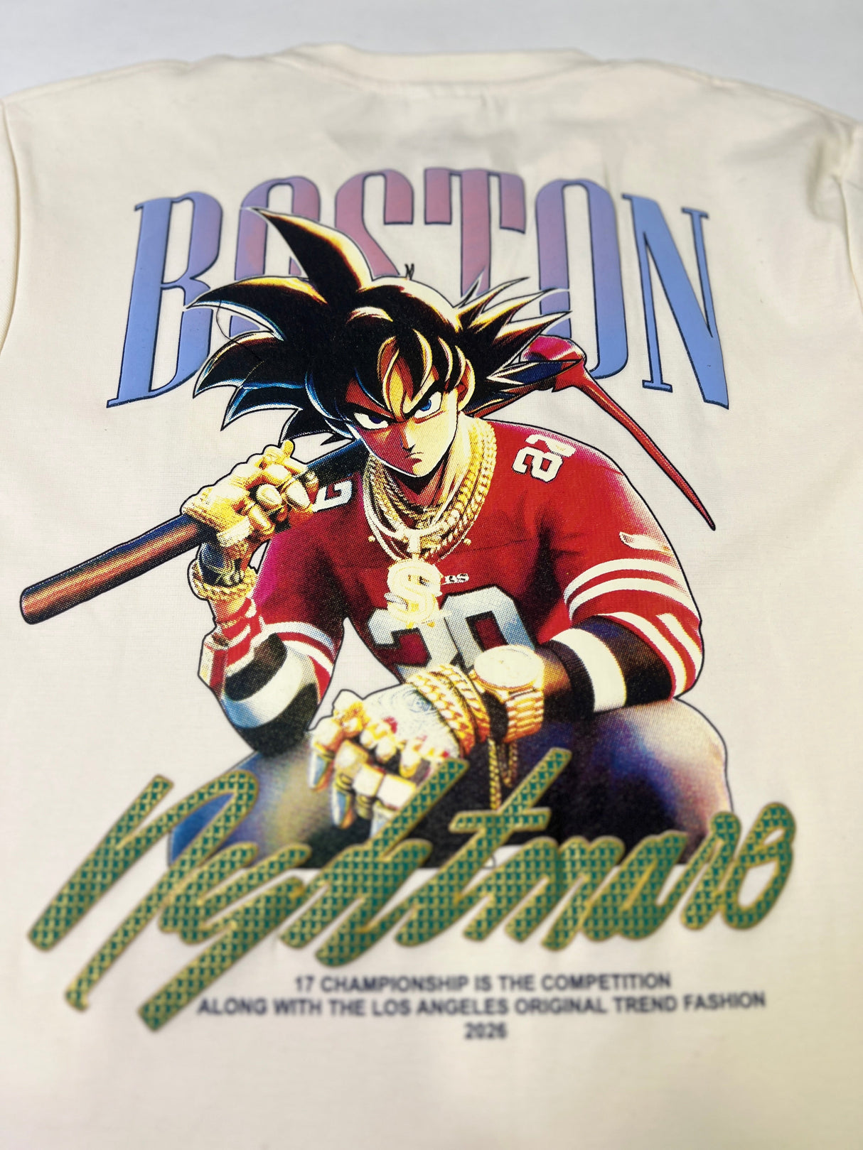 Off-white/cream boys' short-sleeve T-shirt with a light gray brushstroke pattern, featuring the word "MOUNTAIN" in a pink and purple gradient and a motivational quote in white below