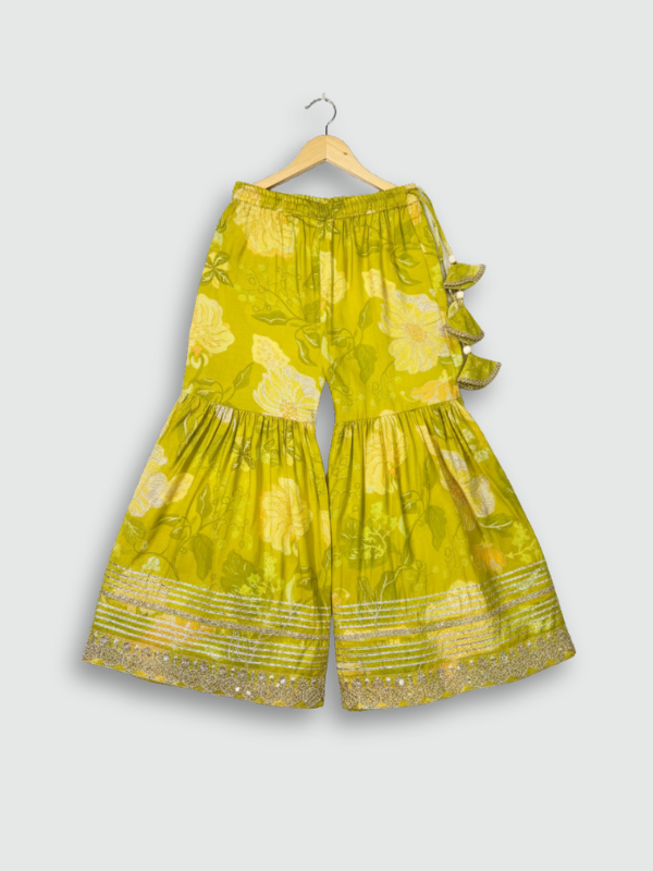 Full set laid flat: lime green kurta with gold embroidery and a floral print, matching tiered sharara pants, and a coordinating dupatta with green tassels.