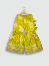 Full set laid flat: lime green kurta with gold embroidery and a floral print, matching tiered sharara pants, and a coordinating dupatta with green tassels.