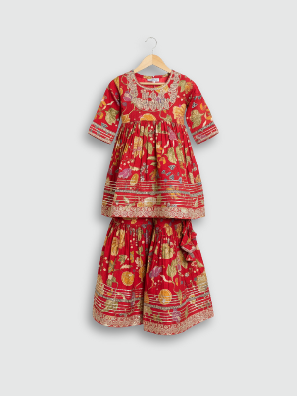 Full set laid flat: a vibrant red, gold-printed kurta with gold embroidered neckline, and matching tiered sharara pants with gold lace detailing.
