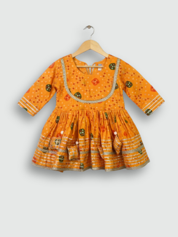 Full set laid flat: a bright orange Bandhani-style printed Angrakha kurta and matching tiered gharara pants with gold and silver metallic lace trimming.