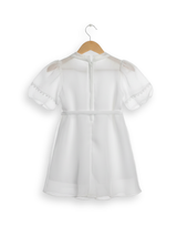 Front view of a girls' white sheer organza short-sleeve frock with painted/appliquéd blue, purple, and yellow floral designs and a matching white tie-belt with tassels.