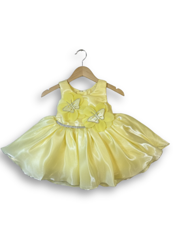 Pale yellow sleeveless girls' party frock on a hanger, featuring a shimmering, full skirt, a silver waistband, and two large yellow flower appliqués with white butterflies on the chest.