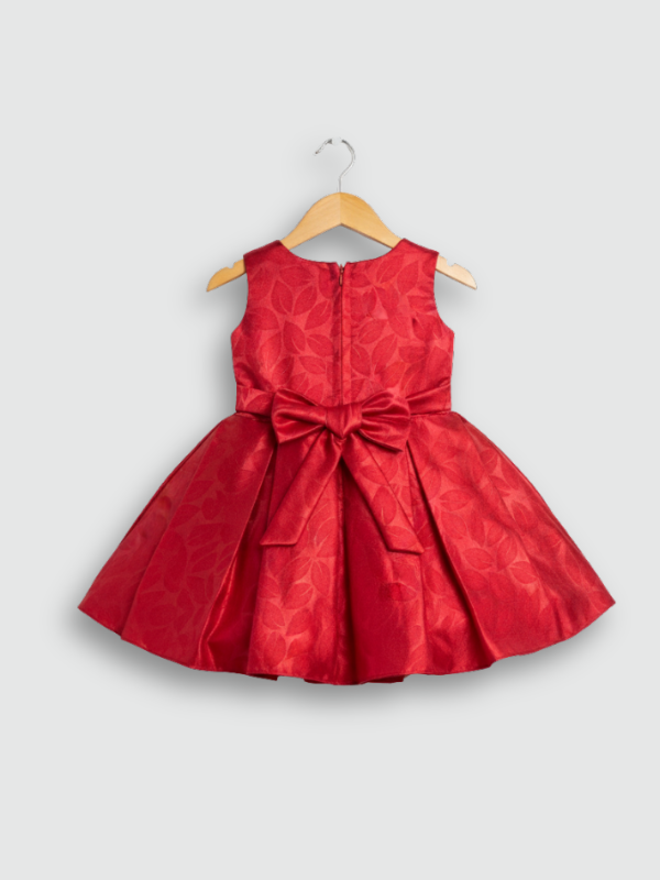 Ruby red girls' sleeveless party frock on a hanger, featuring a textured pleated skirt and a large red 3D flower appliqué with a black center on the bodice.