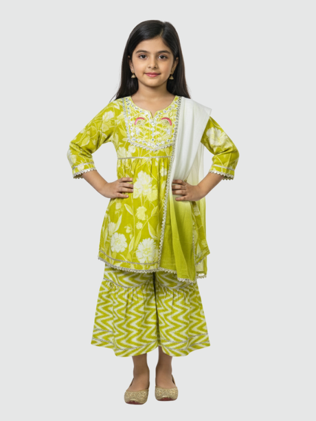 Full-length image of a young girl wearing a lime green and white floral-printed ethnic set with an embroidered peplum top, tiered gharara pants with a zig-zag print, and a white and green dupatta.