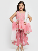 Full-length image of a young girl wearing a powder pink ethnic set with an embroidered sleeveless peplum top, tiered gharara pants with a geometric print, and a pink-to-white ombre dupatta.