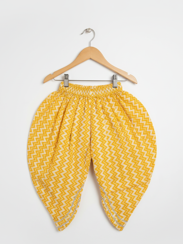 Full-length image of a young girl wearing a yellow ethnic set with a white floral print Angrakha-style top, chevron print dhoti pants, and a white-to-yellow ombre dupatta.