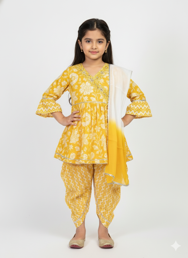 Full-length image of a young girl wearing a yellow ethnic set with a white floral print Angrakha-style top, chevron print dhoti pants, and a white-to-yellow ombre dupatta.