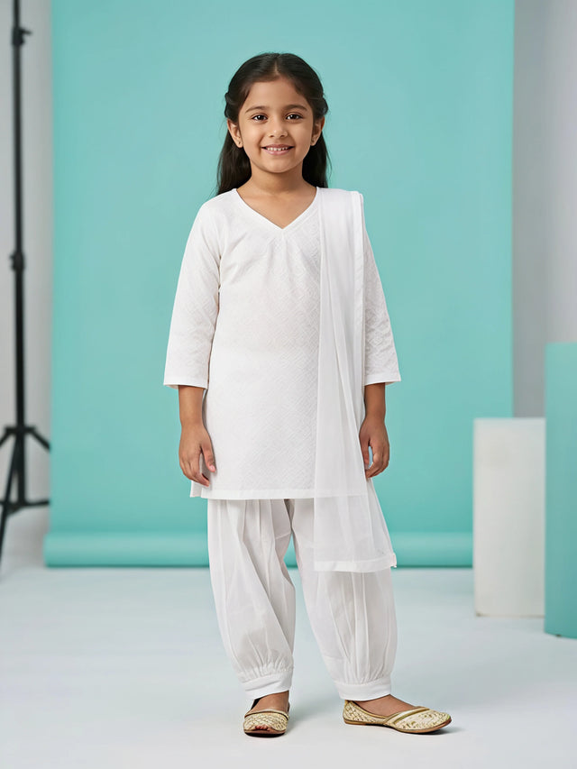 Young girl wearing a classic white textured short kurti with a pleated Patiala salwar and matching draped dupatta