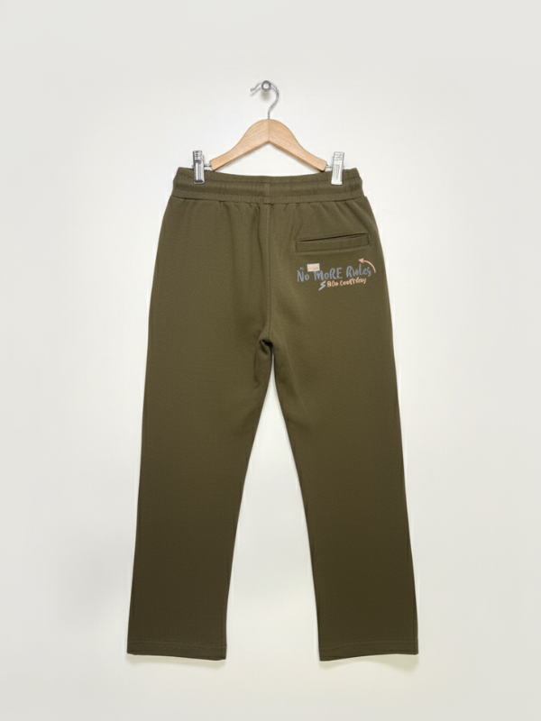 Full-length image of olive green boys' track pants with skate-themed graphics hanging on a white wall.

Export to Sheets