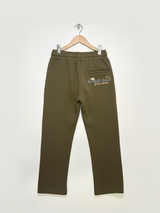 Full-length image of olive green boys' track pants with skate-themed graphics hanging on a white wall.

Export to Sheets
