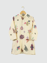 Boys' cream colored kurta with colorful all-over print of geometric and floral motifs, hanging on a wooden hanger.