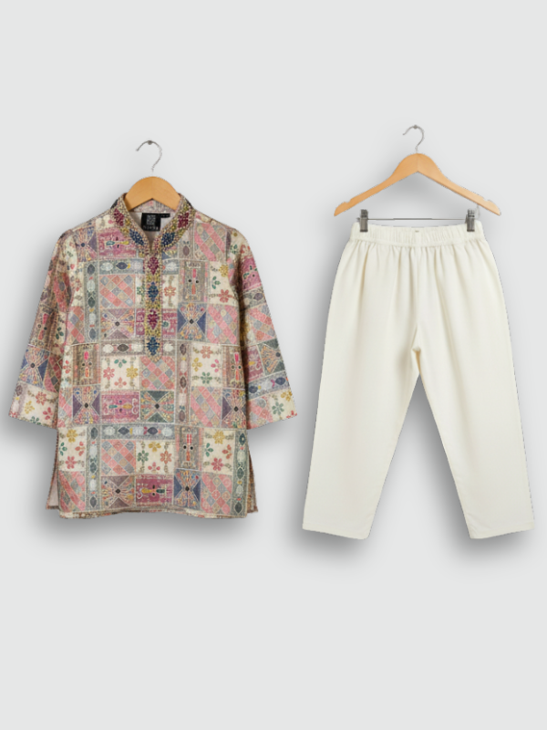 Boys' pink and multicolor geometric printed kurta with embellished neckline and three-quarter sleeves, paired with a cream pajama, hanging on separate hangers.